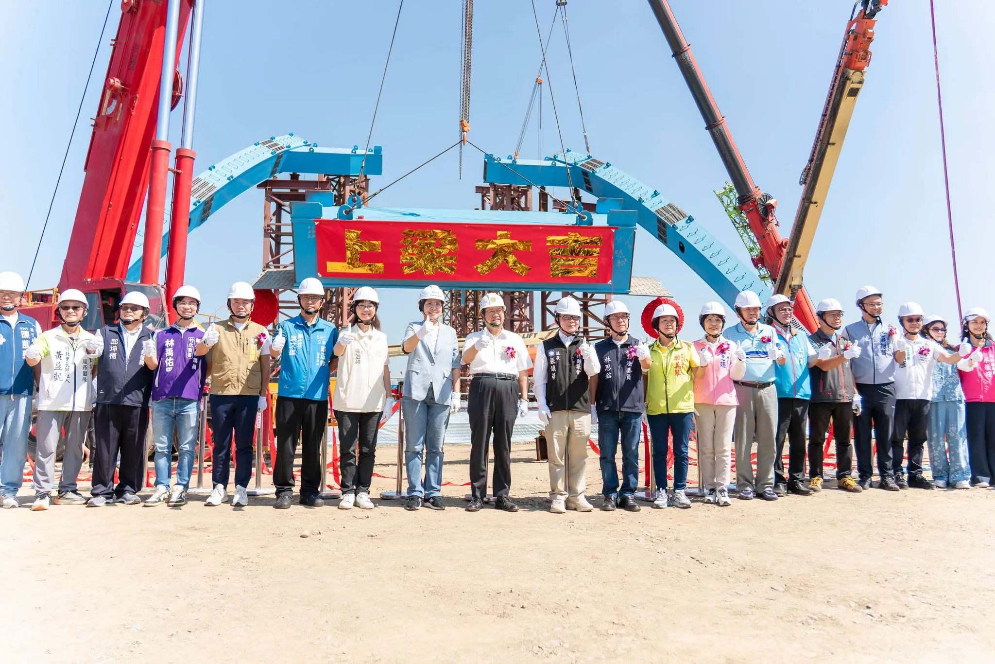 台1線替代道路跨豆子埔溪大橋上樑典禮,工程人員和來賓站在吊起的鋼梁前